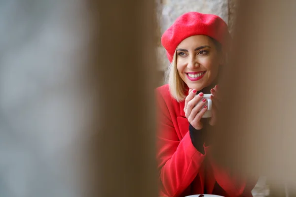 Vrolijke vrouw met koffie in cafe met rode kleren — Stockfoto
