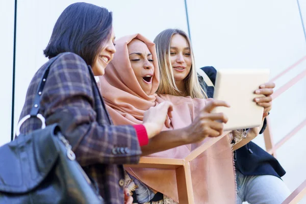 Sorridente giovani ragazze diverse utilizzando tablet sulle scale — Foto Stock