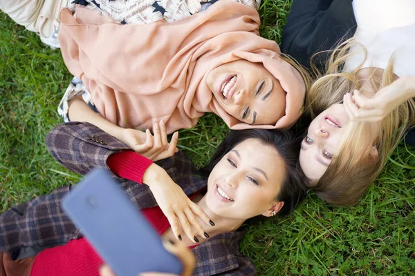 Multiraciální ženy, které spolu v parku dělají selfie — Stock fotografie