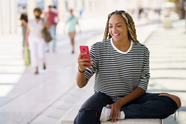 Lachende zwarte vrouw surfen smartphone in de stad — Stockfoto