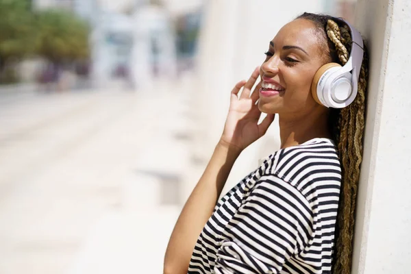 Zwart meisje luisteren naar muziek met draadloze hoofdtelefoon buiten. — Stockfoto