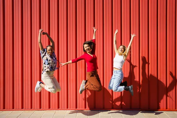 Mulheres encantadas pulando perto da parede — Fotografia de Stock