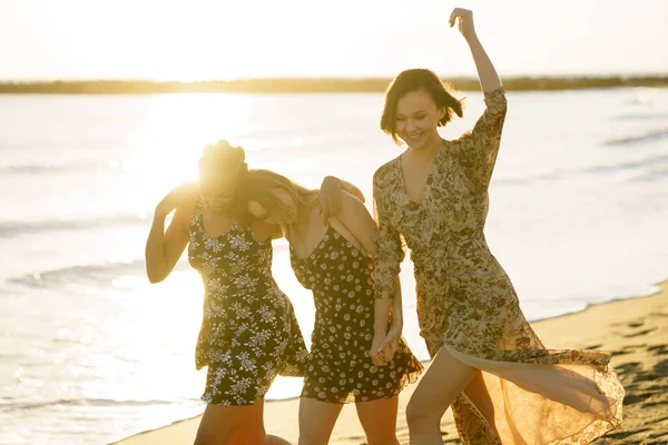 Gelukkig gevarieerde vriendinnen wandelen op het strand — Stockfoto