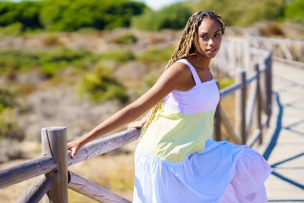 Afrikaanse vrouw draagt een mooie jurk op een promenade op het strand. — Stockfoto