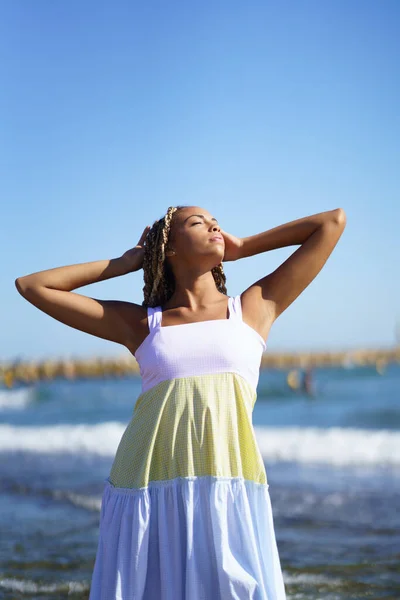 Black woman walking along the shore of the beach wearing a beautiful long dress. — Stock Photo, Image