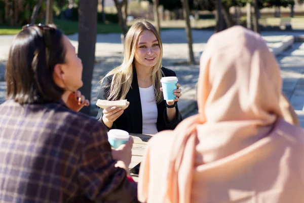 Tres diversas chicas tomando un café y charlando en el parque de la ciudad — Foto de Stock
