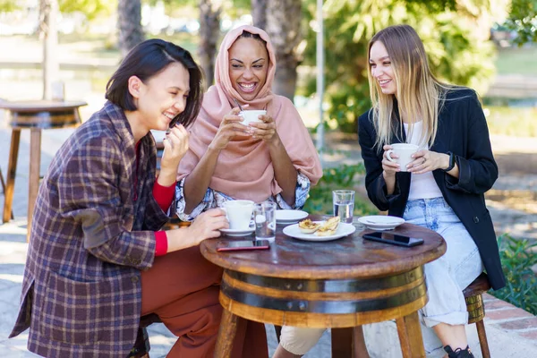 Riendo diversas mujeres tomando un descanso de café en la cafetería al aire libre —  Fotos de Stock