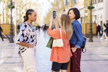 Çeşitli kadınlar sokakta akıllı telefondan selfie çekiyor.