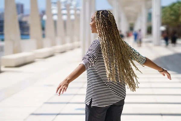 Junge schwarze Frau bewegt ihre farbigen Zöpfe im Wind. Typisch afrikanische Frisur. — Stockfoto