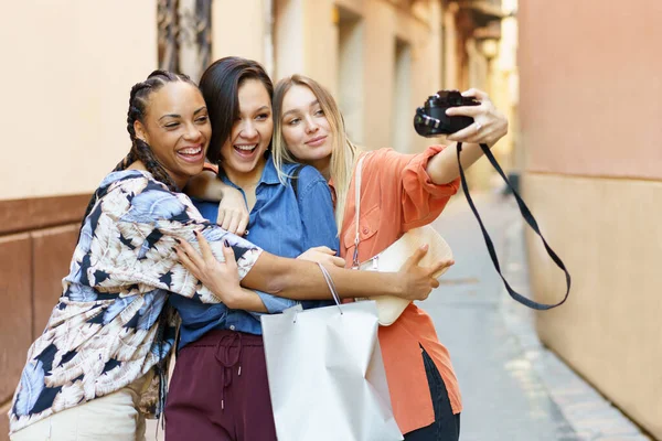 Bezstarostné rozmanité ženy s fotoaparátem tráví čas na ulici — Stock fotografie