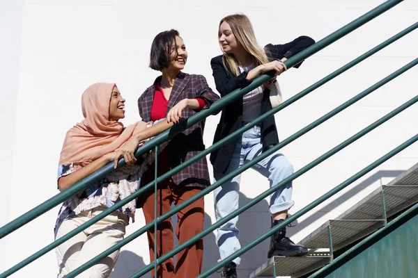 Contenu jeunes femmes diversifiées regardant loin tout en se tenant sur les escaliers dans la ville — Photo