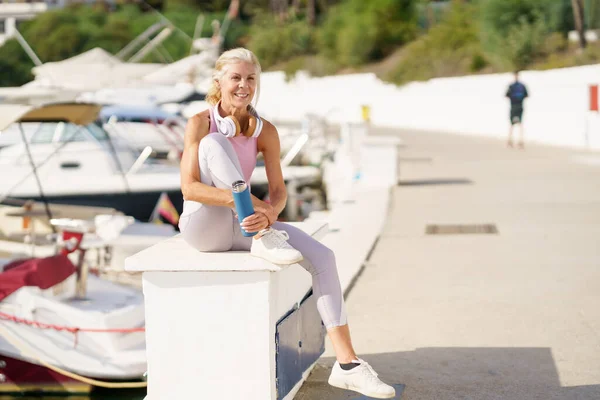 Desportista maduro em roupas fitness beber água de uma garrafa de metal fitness ao ar livre. — Fotografia de Stock