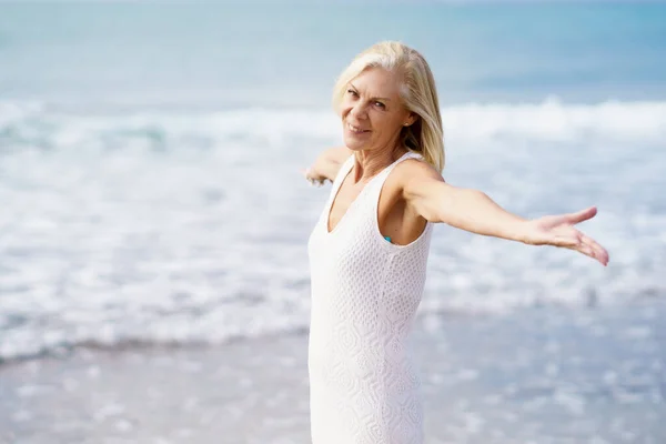 Mature female opening her arms on the beach, spending her leisure time, enjoying her free time — Stock Photo, Image
