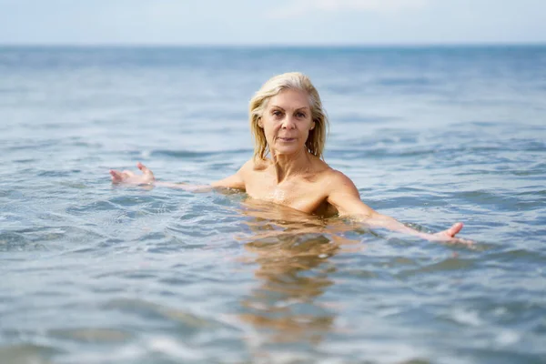 Volwassen vrouw in goede vorm zwemmen in de zee. — Stockfoto