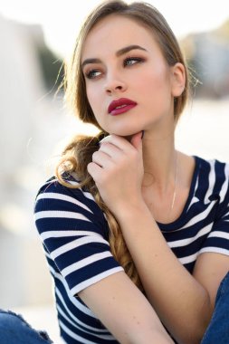 Sarışın kadın, moda, kentsel arka planda oturan modeli.
