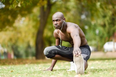 Kentsel arka planda çalıştırmadan önce germe yapan siyah erkek