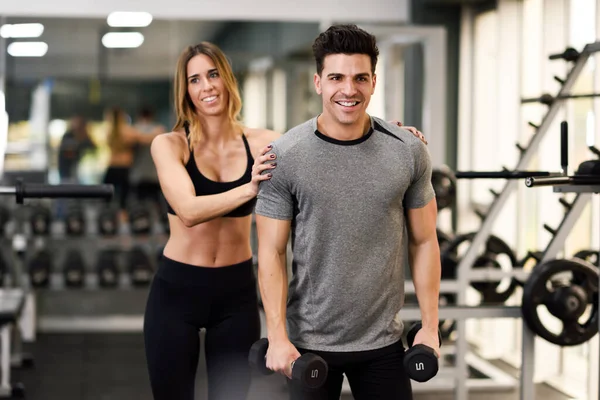 Personal Trainer hilft einem jungen Mann beim Heben von Gewichten — Stockfoto