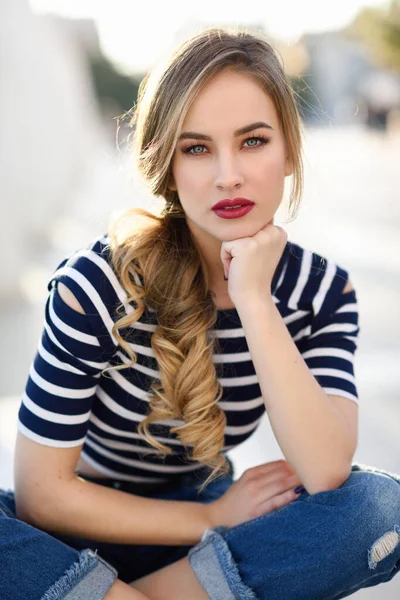 Mujer rubia, modelo de moda, sentada en el fondo urbano . — Foto de Stock