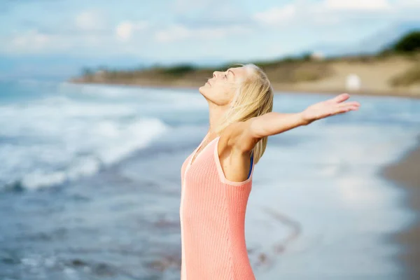 Vacker mogen kvinna öppnar sina armar på en vacker strand, njuter av sin lediga tid — Stockfoto