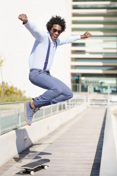 Веселый черный мужчина катается на скейтборде и прыгает — стоковое фото