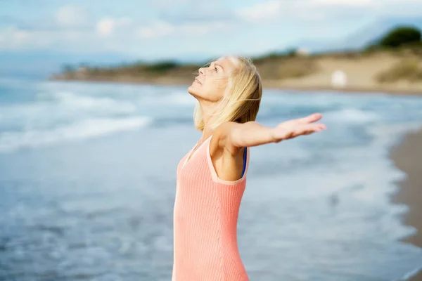 Beautiful mature woman opening her arms on a beautiful beach, enjoying her free time — Stock Photo, Image