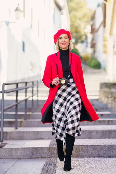 Smiling fashionable woman walking on street with photo camera — Stock Photo, Image