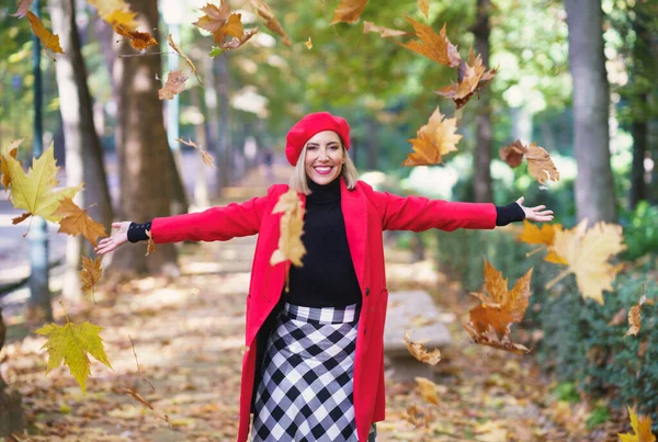 Cheerful woman throwing maple leaves in air — ストック写真