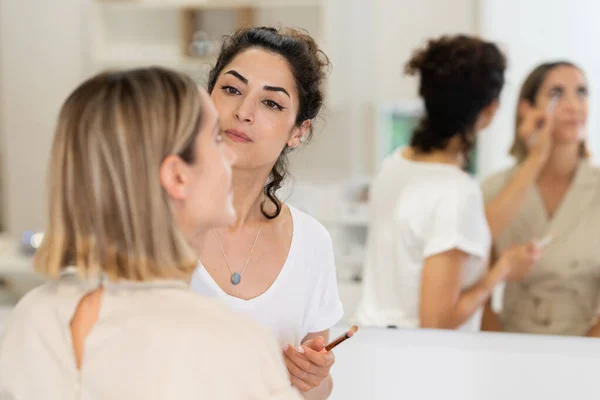 Artista de maquillaje árabe que compone a una mujer en un centro de belleza. —  Fotos de Stock