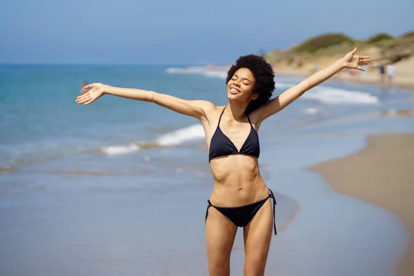 Pozitív afro-amerikai nő tárja karjait a parton, hogy élvezze a nyaralás a napon. — Stock Fotó