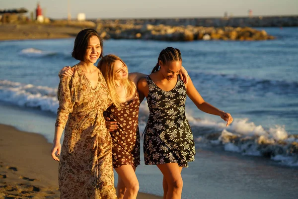 Diverse vriendinnen wandelen in de buurt van wuivende zee — Stockfoto