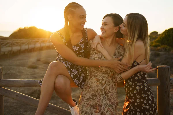 Счастливые разнообразные девушки обнимаются у забора — стоковое фото