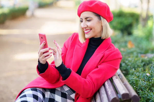 Happy Female Stylish Red Outfit Surfing Cellphone While Sitting Wooden —  Fotos de Stock