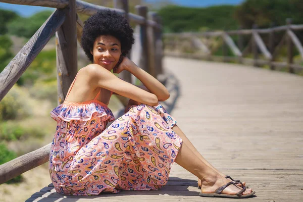 Glad African American Woman Ornamental Dress Sandals Touching Curly Hair — Stock Fotó