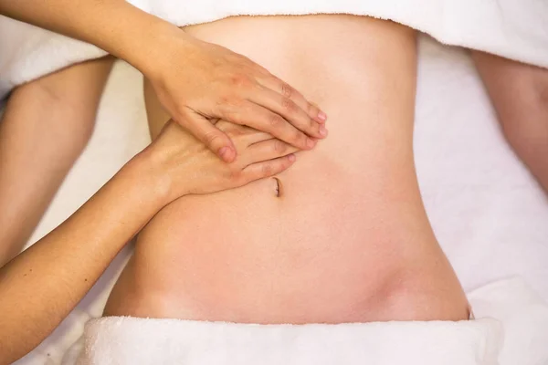 Top view of hands massaging female abdomen.Therapist applying pressure on belly