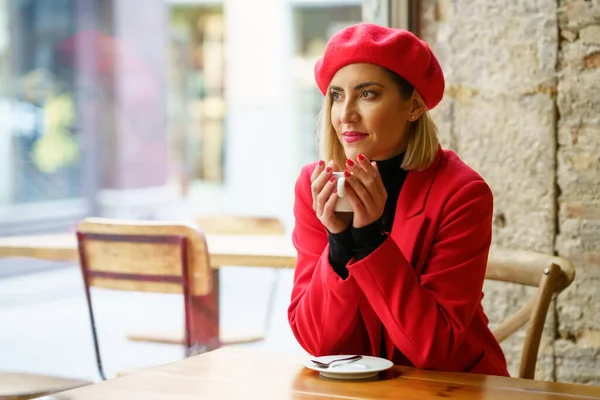 Dreamy Female Red Outfit Looking Distance While Sitting Table Window — Stock fotografie