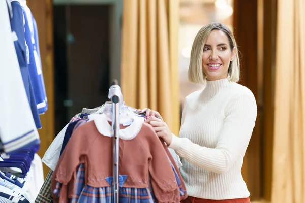 Positive Female Shopper Selecting Child Clothes Rack Store Shopping Mall — Stockfoto