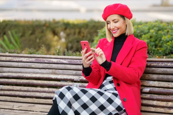 Восхитительная Женщина Красном Пальто Берете Прокручивает Новости Современному Сотовому Телефону — стоковое фото