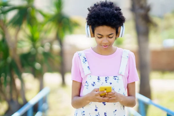 Contenido Mujer Afroamericana Escuchando Canciones Auriculares Inalámbricos Mientras Desplaza Teléfono —  Fotos de Stock