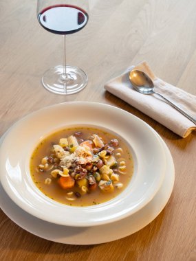 İtalyan Sebze Çorbası Beyaz Tabakta Kaşık ve Şarap Kadehiyle