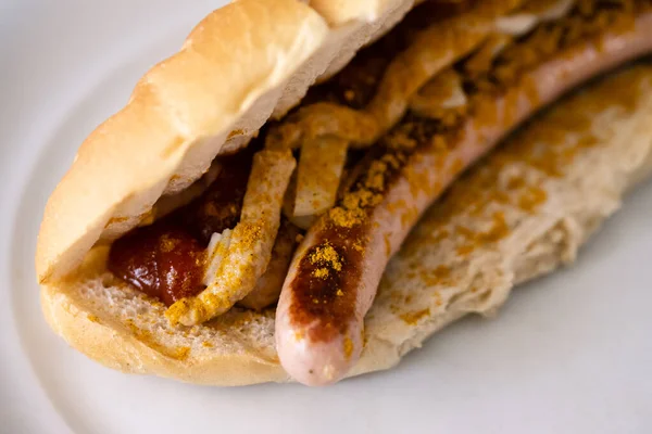 Bosna or Bosner Spicy Austrian Style Hot Dog with grilled Bratwurst, Onions, Tomato Ketchup and Curry in Selective Focus
