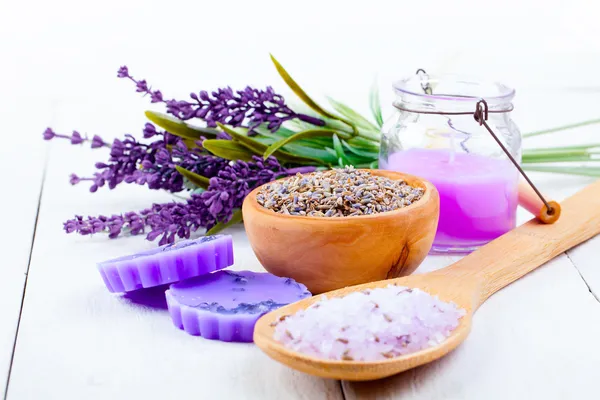 Erbe secche di lavanda, sale da bagno e candela, su tavolo di legno bianco — Foto Stock