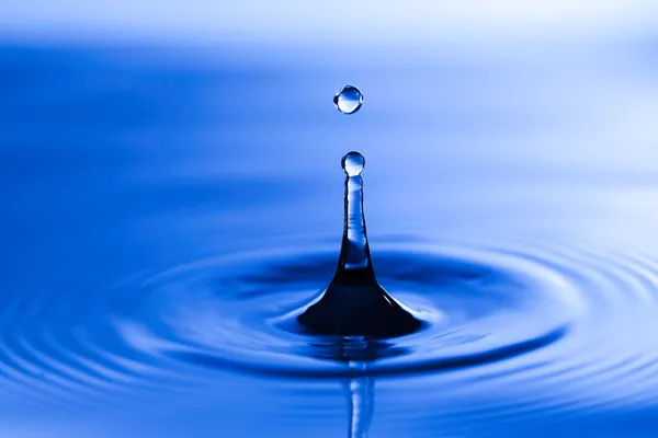 Gota de água caindo em uma superfície líquida — Fotografia de Stock