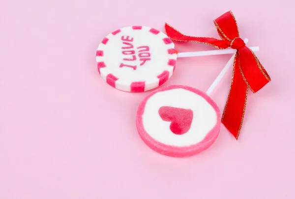 Twee valentine lollys, op roze achtergrond. met rode satijnen lint gebonden — Stockfoto