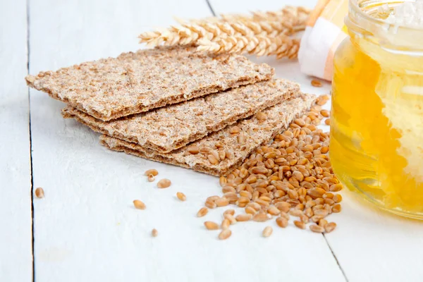 Honig mit einem Kochlöffel und Knäckebrot auf Holzgrund — Stockfoto