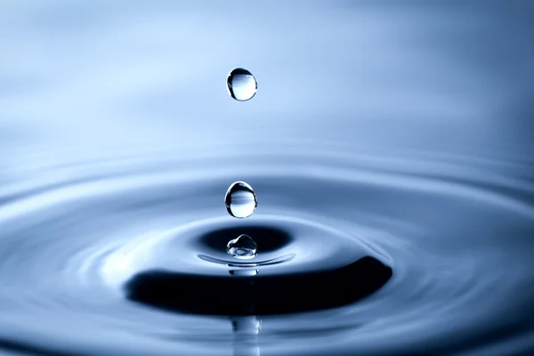 Gota de água caindo em uma superfície líquida — Fotografia de Stock