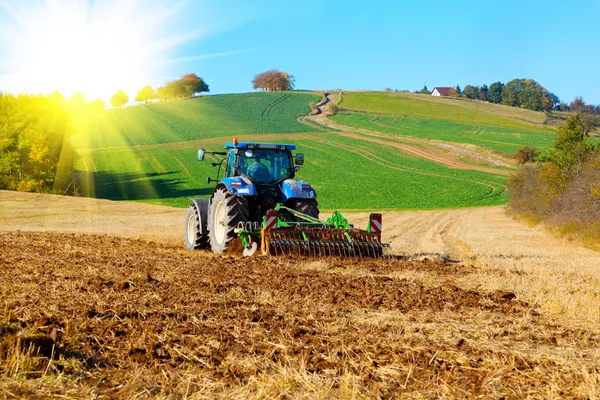 Tractor arada un campo en primavera, con luz solar Imagen de archivo