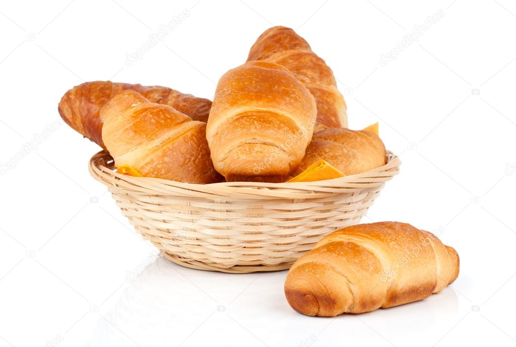 Fresh and tasty croissant in a straw basket, isolated on the white background