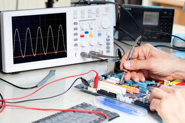 Tech tests electronic equipment in service centre — Stock Photo, Image