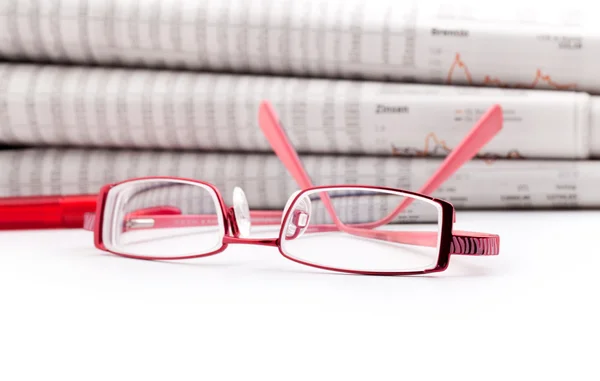 Reading glasses lie before a big newspaper pile — Stock Photo, Image