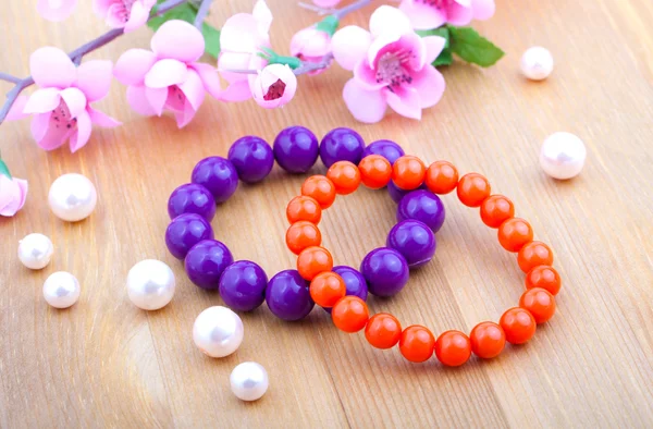 Multi color coral bangles and artificial pearls, with pink flowe — Stock Photo, Image